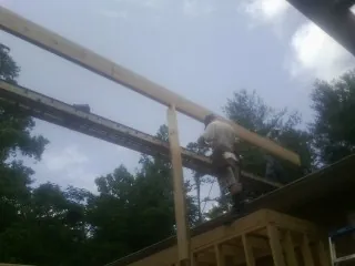 Carpenter setting a ridge beam over a new addition frame — Ice Dam Removal by Roofing Brothers in Greencreek