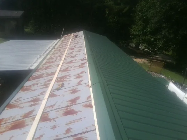 Old rusted panels beside newly installed green metal roofing — Wind Damage Roof Repair by Roofing Brothers in Greencreek