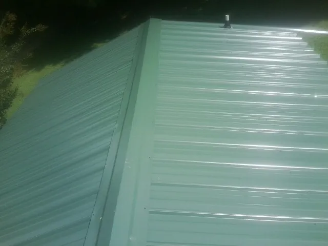 New green metal panels meeting at the ridge of a roof — Flat Roof Repair work by our crew in Greencreek