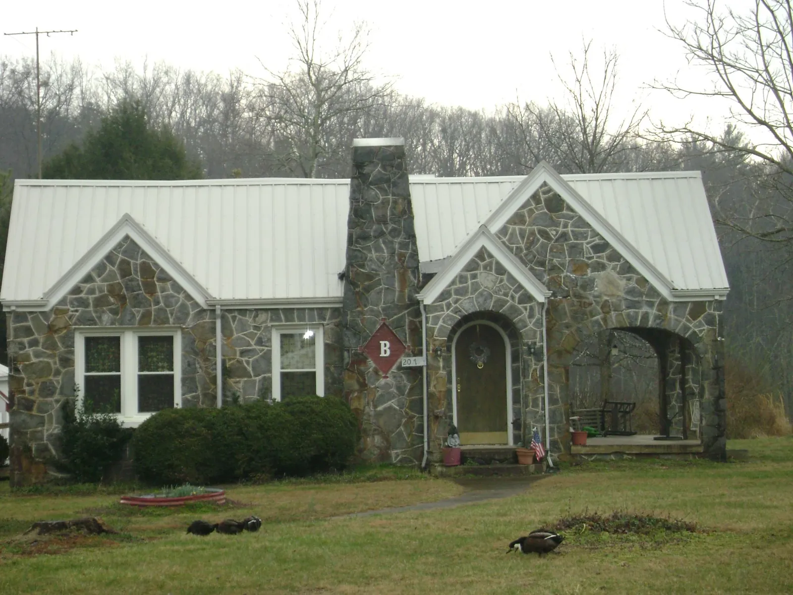 White metal roof on a stone cottage with steep gables in Greencreek