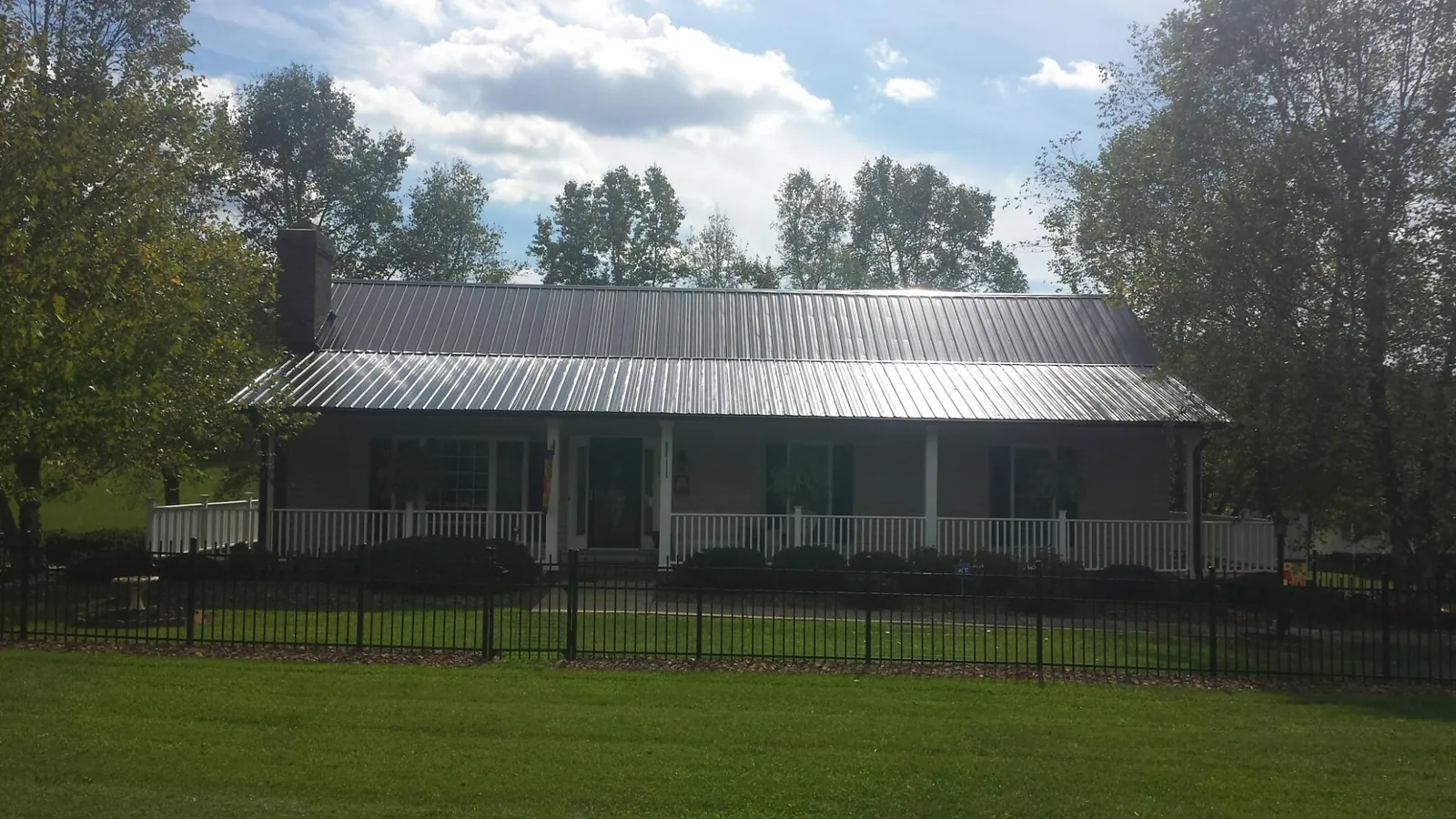 Gray metal roof on a brick ranch with a full width front porch — Gutter Guard Installation work by our crew in Greencreek