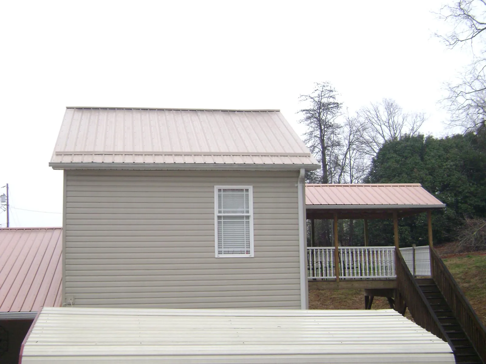Tan metal roofs on a two story addition and attached porch, from a Roof Replacement job in Greencreek