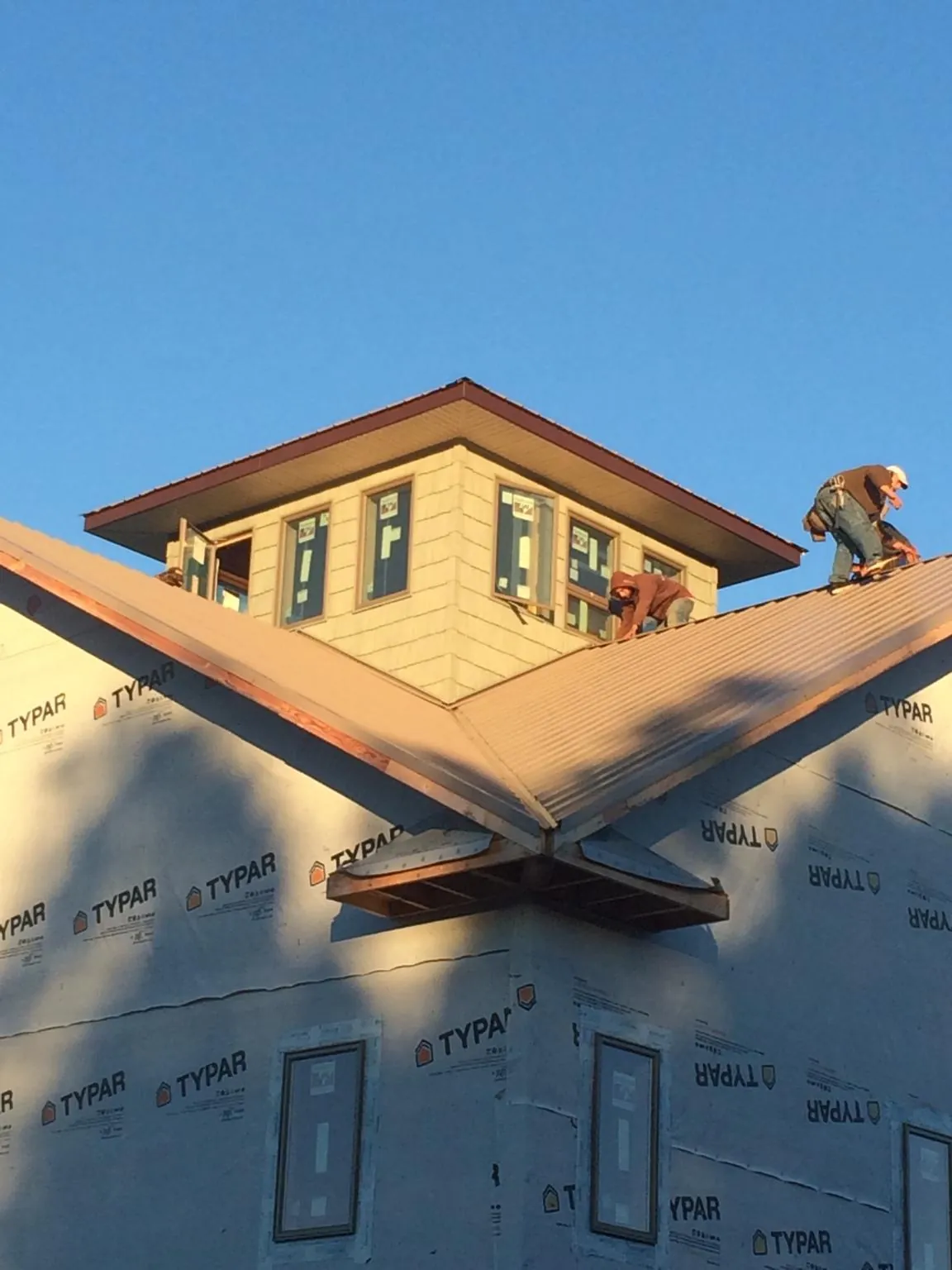 Roofers working around a rooftop cupola on a new metal roof at sunset — Roof Waterproofing in Greencreek by Roofing Brothers